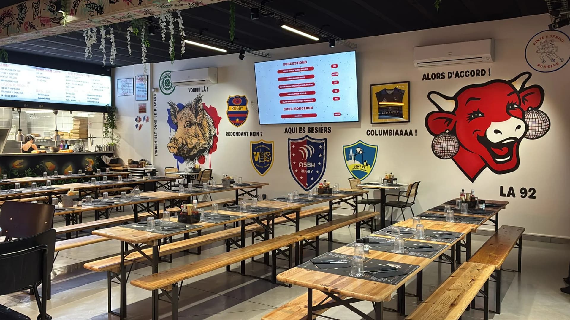Intérieur du restaurant avec fresque vache rouge et écussons rugby ASBH